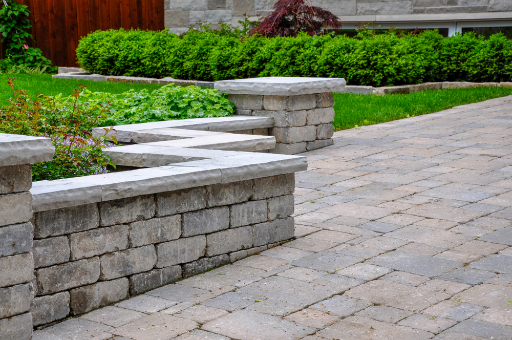 Hardscaping service's seat wall with pillars and natural stone coping, providing a stylish and comfortable outdoor seating area.